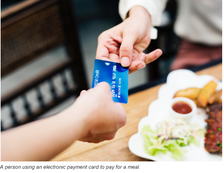 A Person Using An Electronic Payment Card To Pay For A Meal A Person Using An Electronic Payment Card To Pay For A Meal