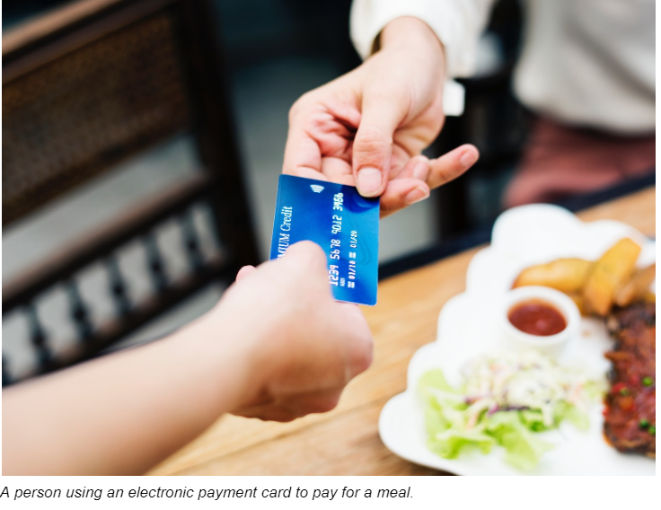 A Person Using An Electronic Payment Card To Pay For A Meal