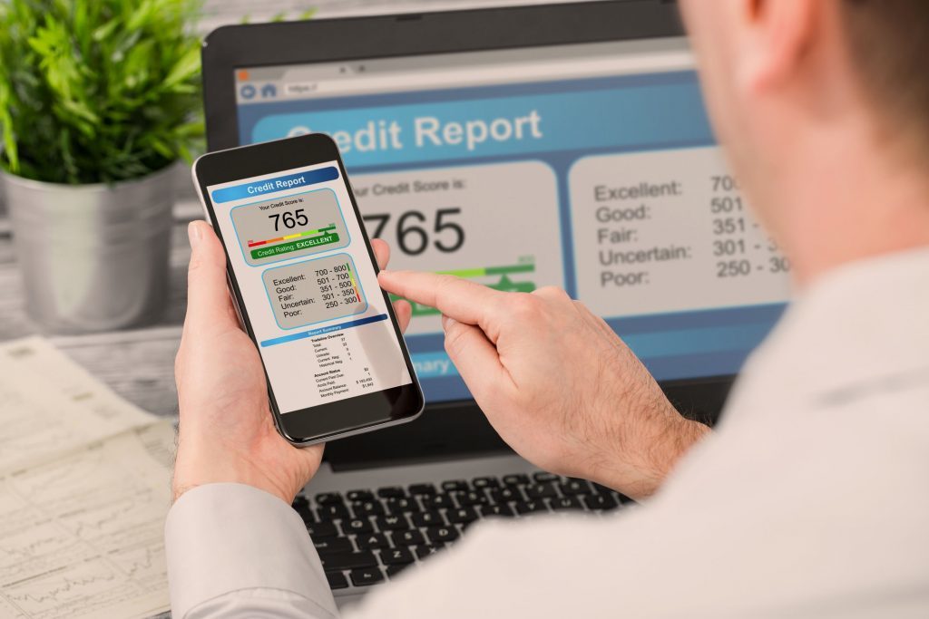 Man holding a smartphone calculating his average credit score.