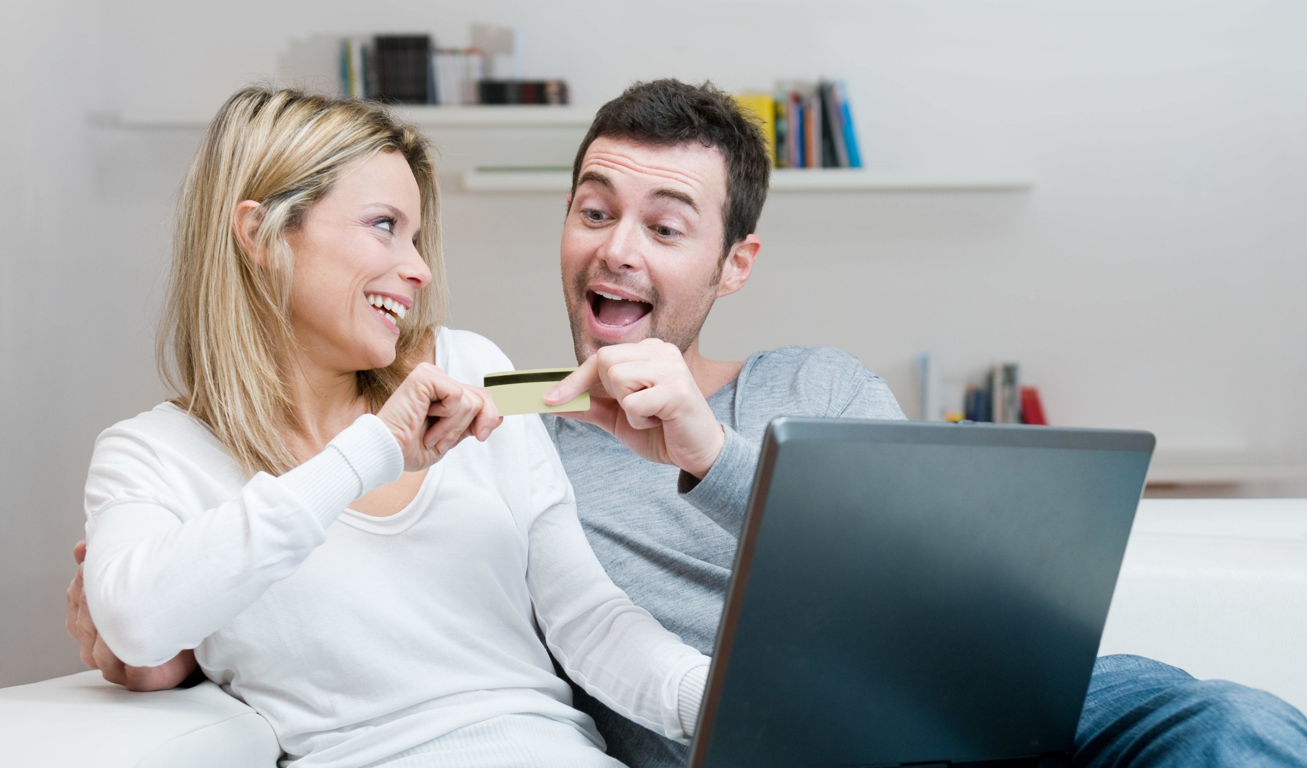 A couple smiling as they're holding their joint credit card.