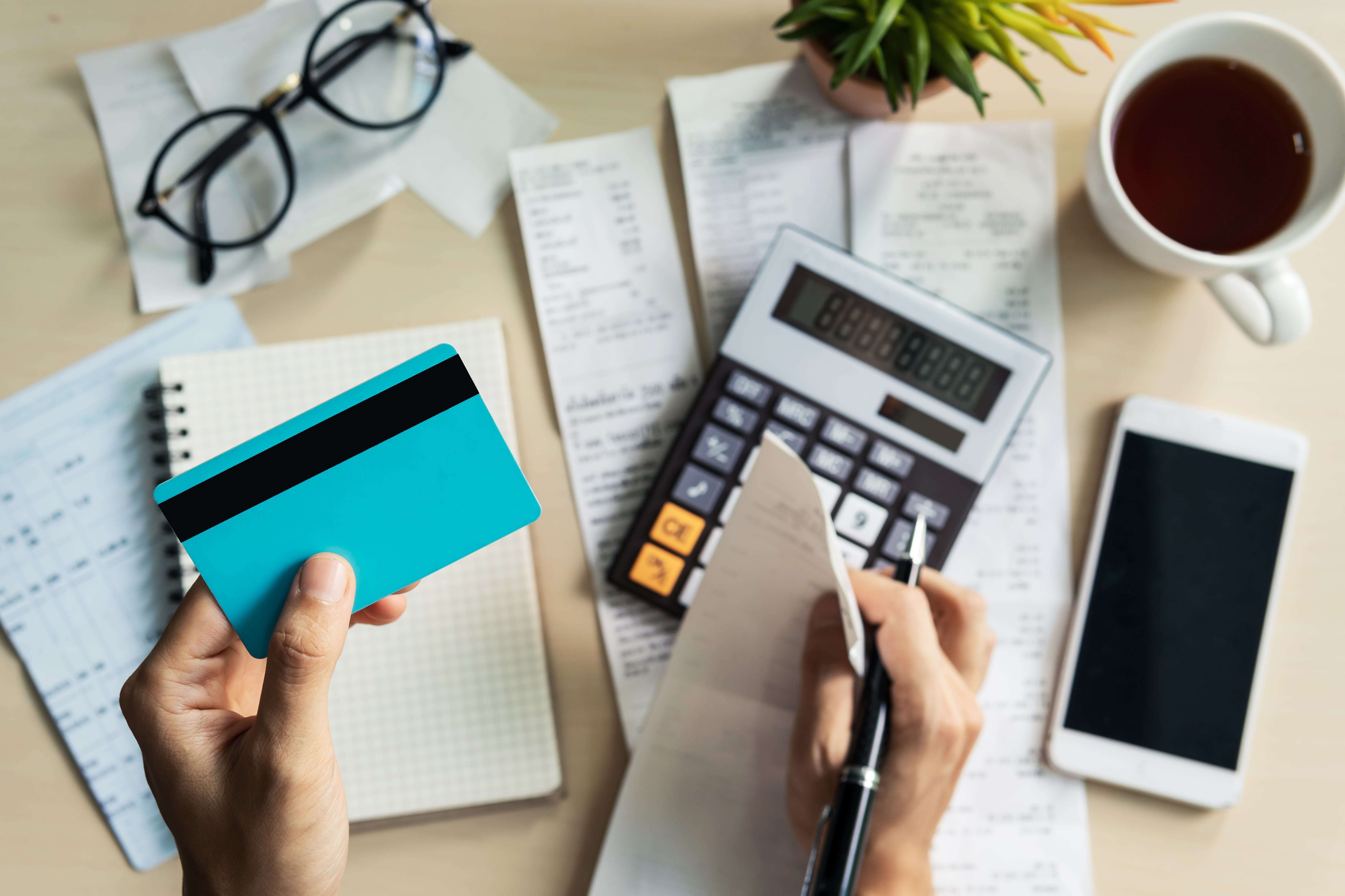 Doucments and credit cards scattered around a calculator to make credit utilization calculations.